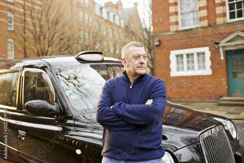 Portrait of taxi driver in front of his cab