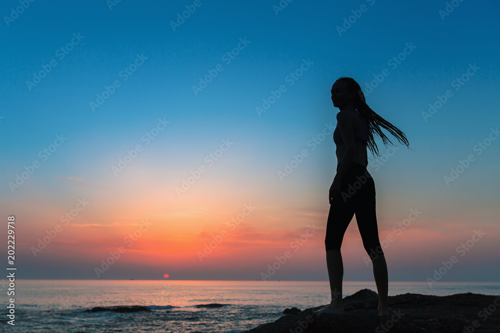 Silhouette flexible girl on the shore of Sea during twilight.