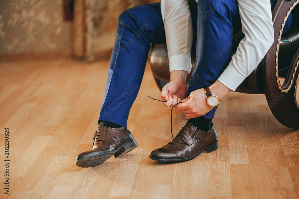 the groom wears shoes on wedding preparations
