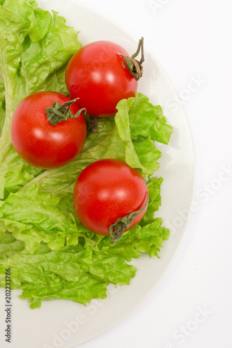 cherry tomatoes, lettuce leaves on a white plate