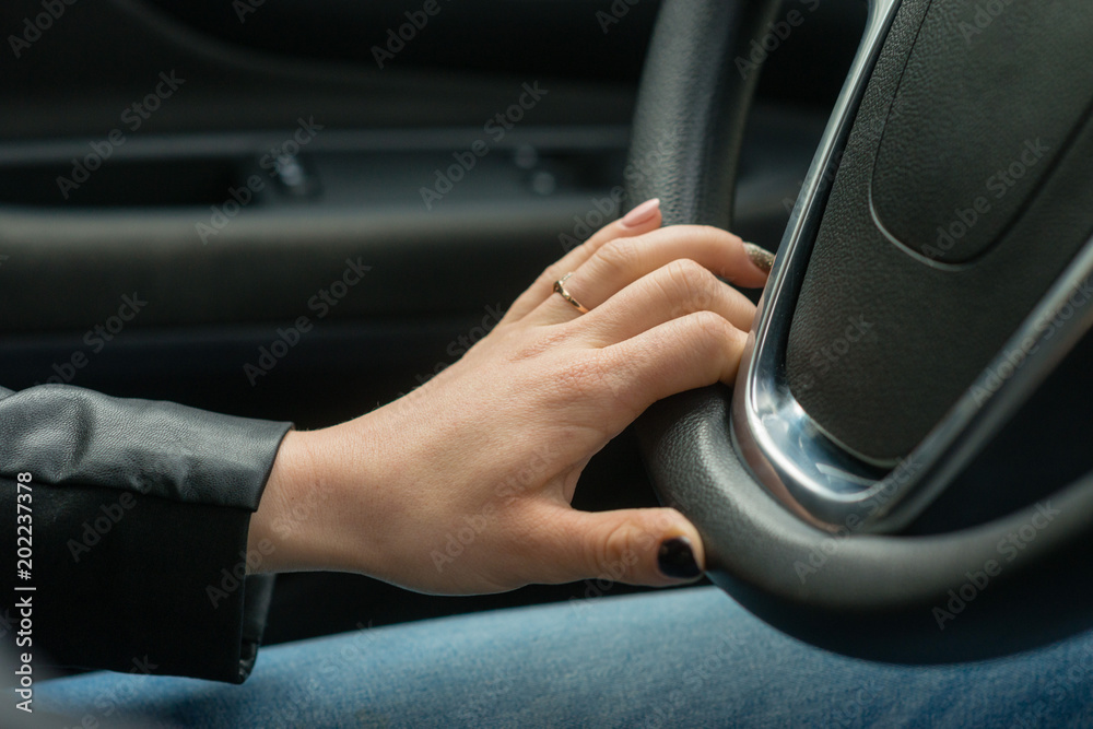 Women hands on the car's steering wheel.