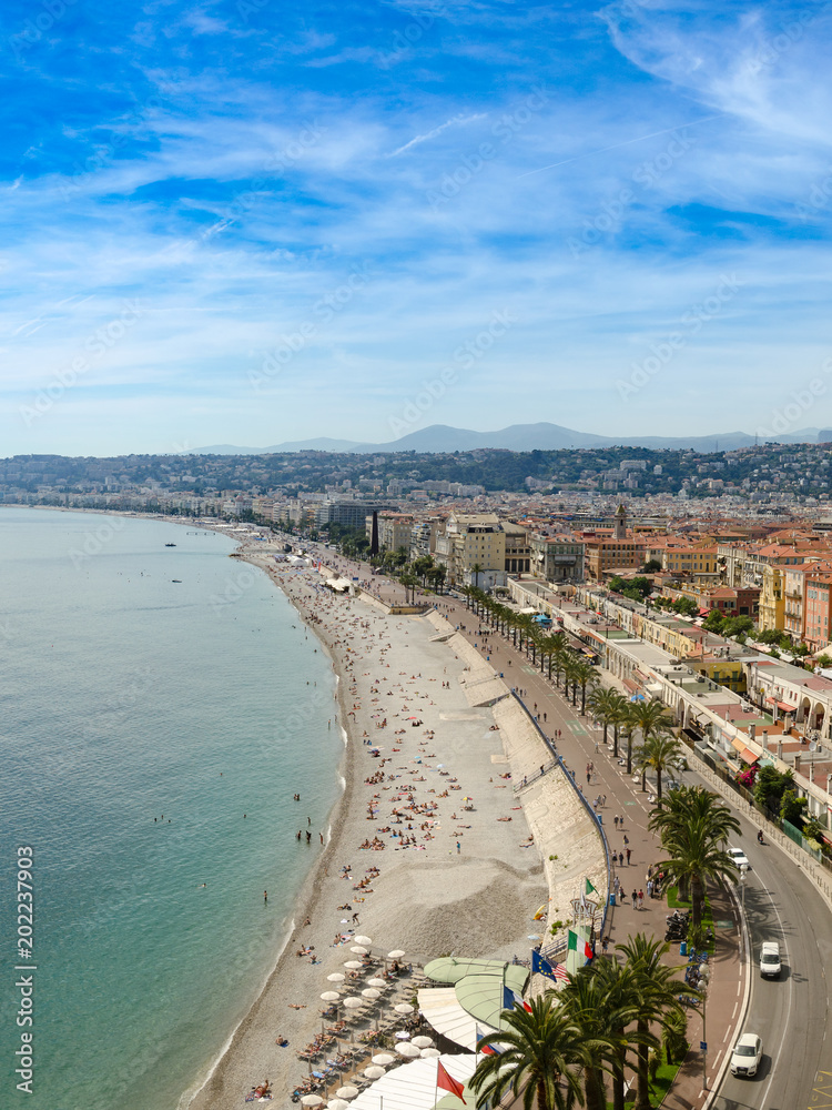 Luxury resort of French riviera. Beautiful panorama city of Nice in France. Sunny, summer day. Mediterranean sea, public beach, famous quay, palms and houses of Nice