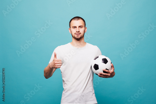 Portrait of young man holding a soccer ball isolated on green background