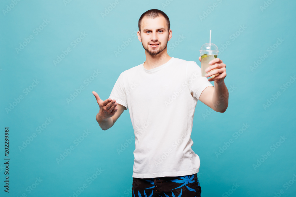Handsome young man with bottle with summer drink and looking at camera isolated on green