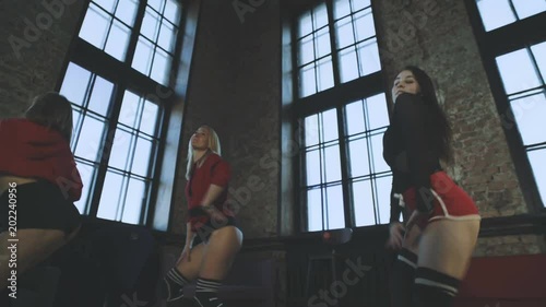 Three beautiful girls are dancing twerk in a hall. Booty shake.
