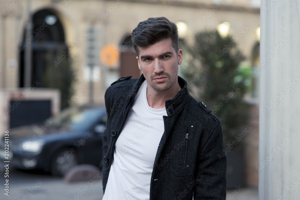 handsome young man with black jacket standing on the street handsome young man with black jacket standing on the street