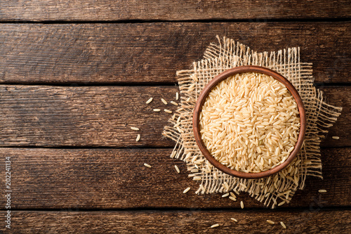 Valokuva Raw brown rice in ceramic bowl on dark rustic wooden background