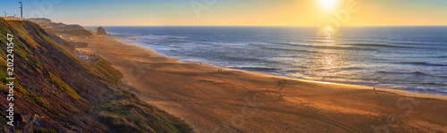 Wonderful romantic sunset panoramic landscape coastline of Atlantic ocean. View Mirante beach in Santa Cruz in low season at sunny weather. Fishermen catch fish. People are walking. Silveira. Portugal