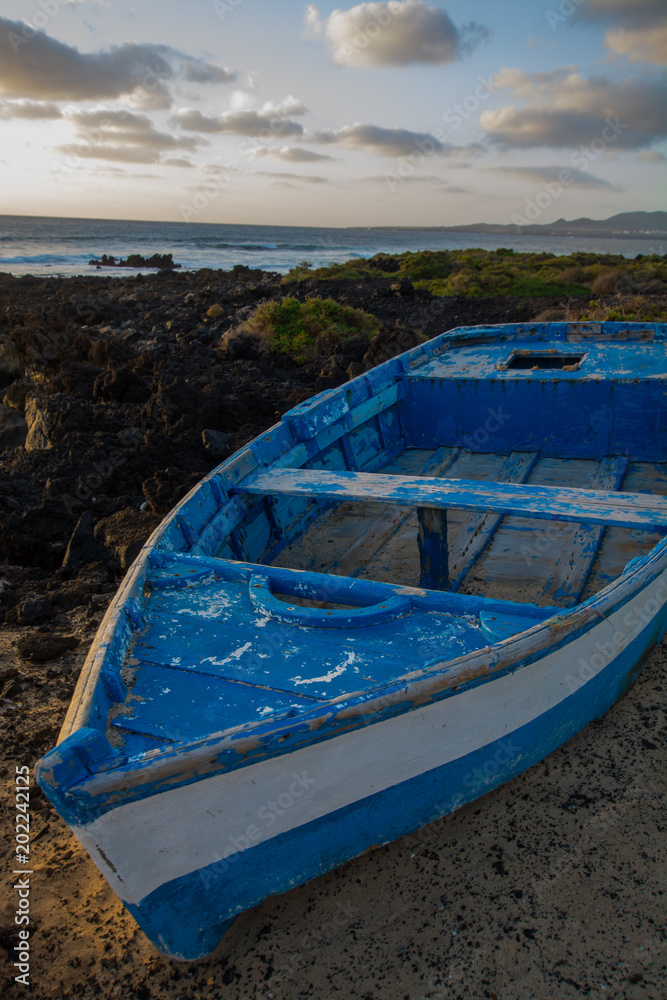 Sunset over the sea landscape with old blue wooden fishing boat Sunset over the sea landscape with old blue wooden fishing boat