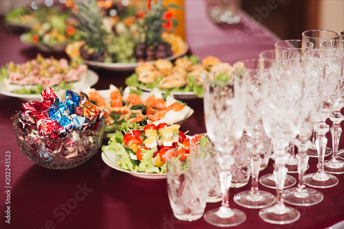 Beautifully decorated catering banquet table with burgers, profiteroles, salads and cold snacks. Variety of tasty delicious snacks on the table