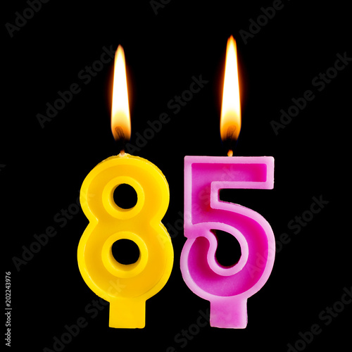 Burning birthday candles in the form of 85 eighty five figures for cake isolated on black background. The concept of celebrating a birthday, anniversary, important date, holiday