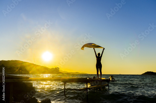 Beautiful Girl With White fabric on The Beach Pier against Sunset. Travel and Vacation. Freedom Concept © zefart