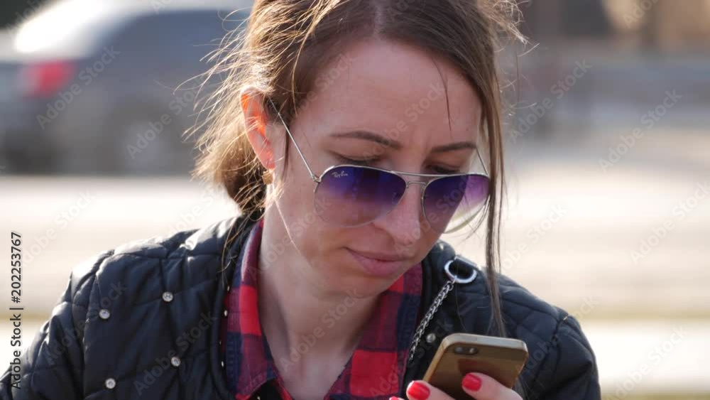 Young woman use phone in the park sitting on a bench. Young woman use phone in the park sitting on a bench.