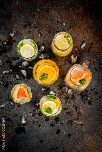 Summer healthy cocktails, set of various citrus infused waters, lemonades or mojitos, with lime lemon orange grapefruit, diet detox beverages, in different glasses dark background copy space above