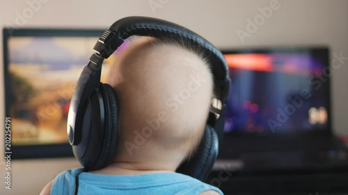 Baby boy in headphones playing the computer game. The concept of computer addiction, selective focus. photo