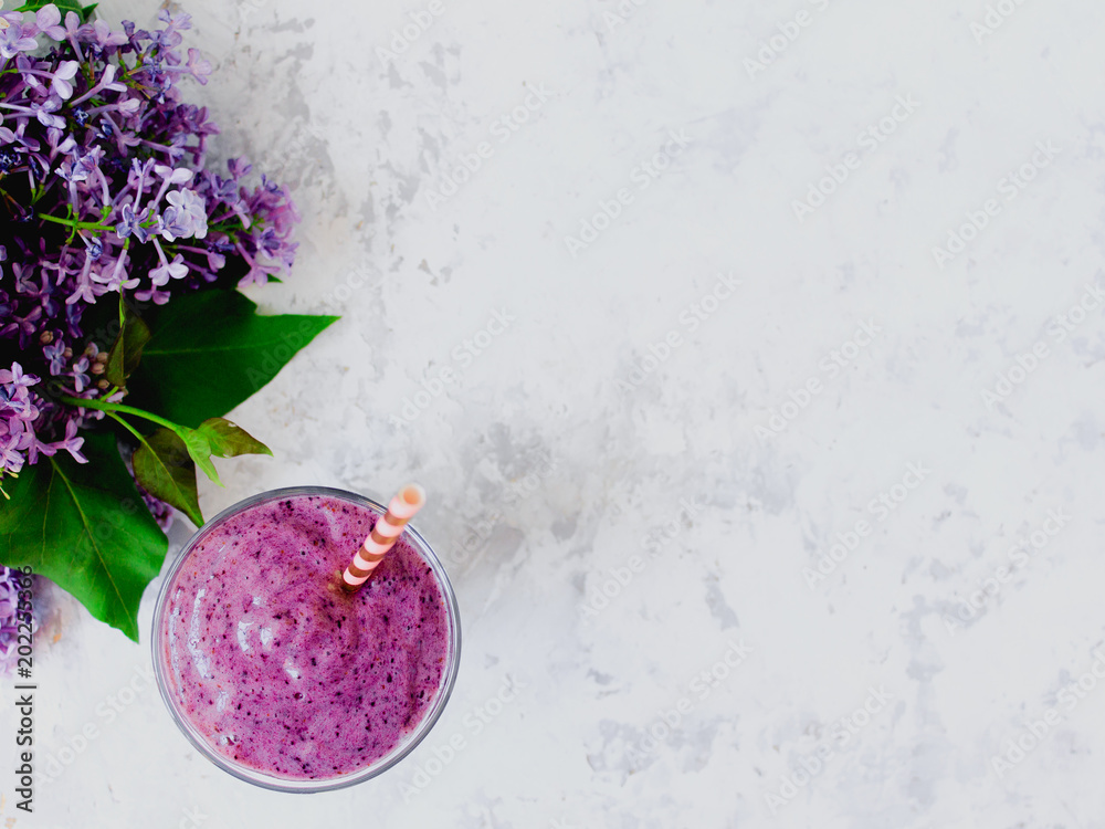 Still life of purple blueberry smoothie with stripped straw and a branch of lilac in glass on white textured background. Healthy vegan lifestyle concept. - obrazy, fototapety, plakaty 