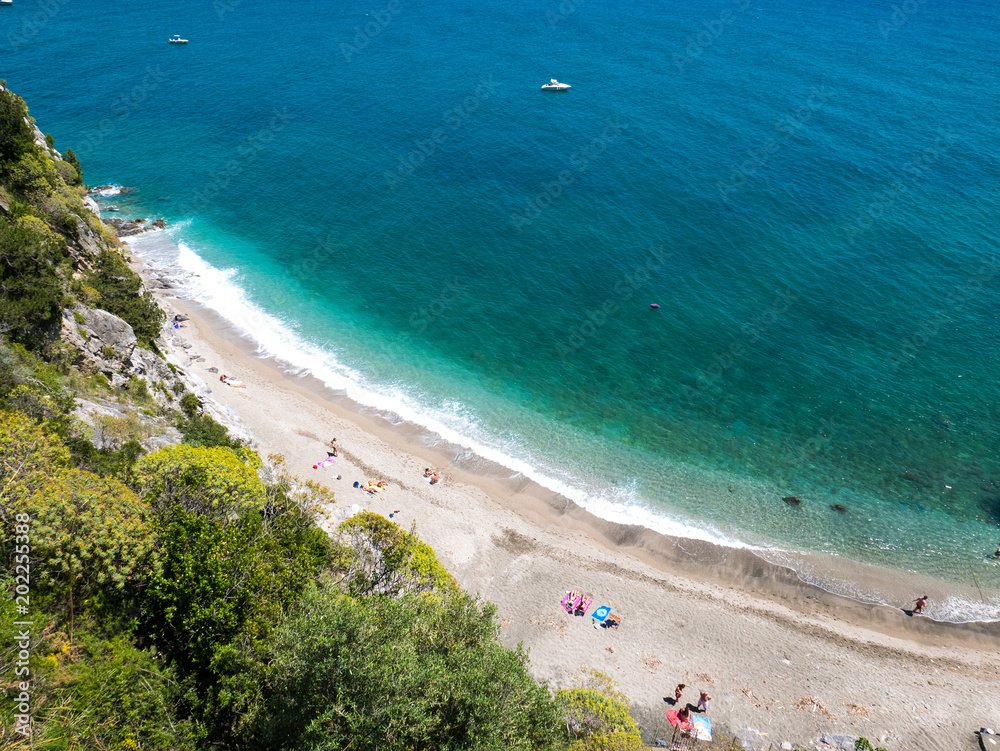 Obraz premium Amalfi Coast, Naples, Italy. Abstract aerial view of a secret beach, with white pebbles and turquoise sea water, surrounded by green trees and almost desert beach with no people.