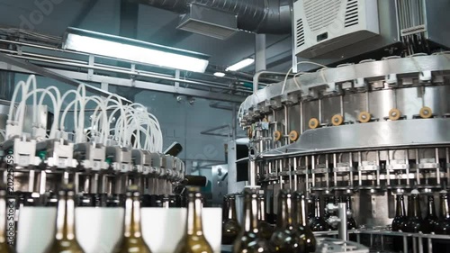 Automatic filling machine pouring beer in a brewery. Glass bottles for beer on the conveyor belt. Filling machine for industry.