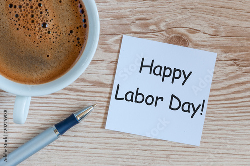 Happy labor Day - message on wooden table background with morning coffee mug. Labour day celebrated at May 1. Spring time