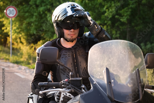 rider on a motorcycle taking off his helmet - summer road trip on a motorbike © Melinda Nagy