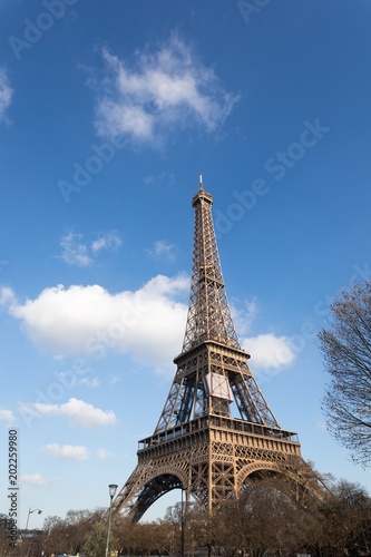 Tour Eiffel against blue sky and white clouds. The metal structure landmark has become the symbol of Paris and France. Feb 2018.