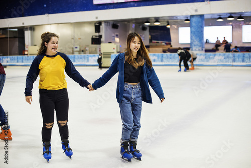 Girl friends ice skating on the ice rink together