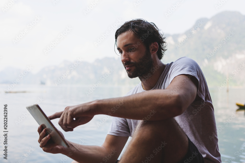 Man using his phone by a lake