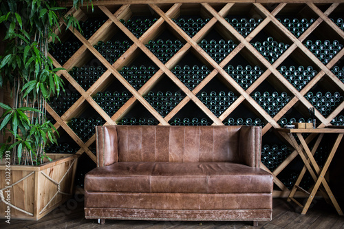 Bottles of wine in a wine cellar. Old brown vintage sofa