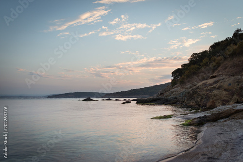 Beautiful landscape on the beach, sunset and soft color sky. Scenic view on hills and calm sea in the evening.