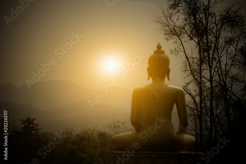 Fototapete Buddha Statue on the mountain with sunset background