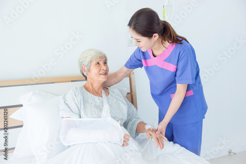 Senior asian female patient smiling with nurse who come to visit her at bed