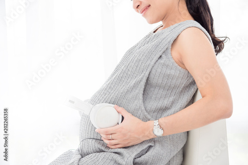 Pregnacy woman put headset on her belly and smiles photo