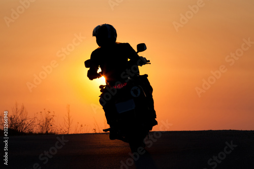 silhouette of rider on a motorbike driving at sunset - space for your text © Melinda Nagy