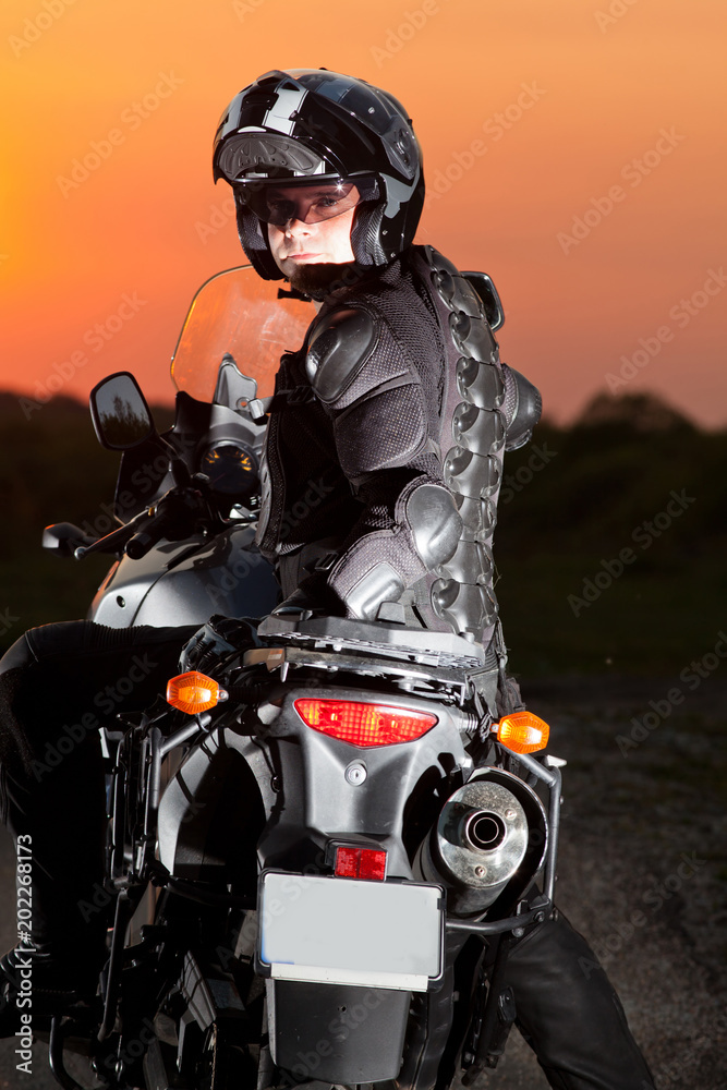 man on his motorbike admiring sunset - summer road trip - space for text