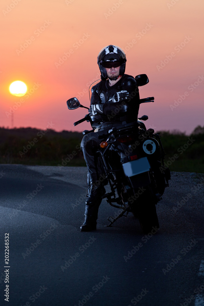 man on his motorbike admiring sunset - summer road trip - space for text