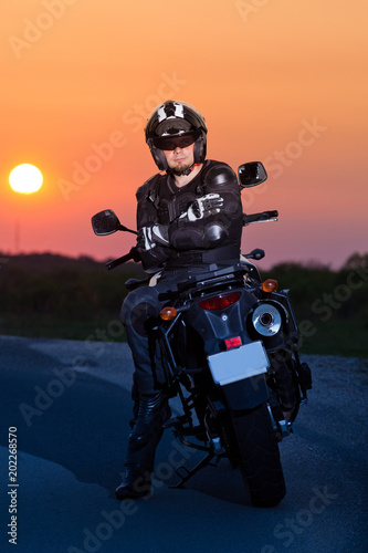 Fototapeta Naklejka Na Ścianę i Meble -  man on his motorbike admiring sunset - summer road trip - space for text