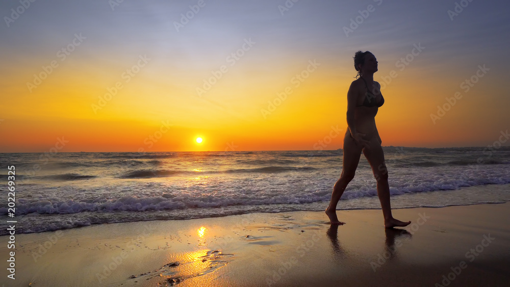 Girls run out of ocean water at sunset on tropical beach