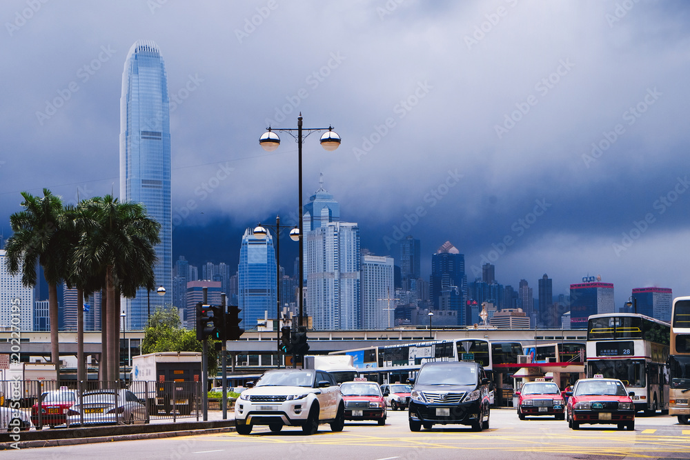Busy traffic in downtown Hong Kong with clouds among skyscrapers in background