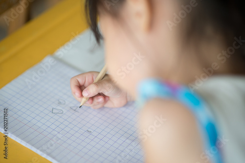 Little asian girl writing in the notebook school class