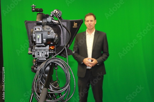 Man reading autocue teleprompter against green screen photo