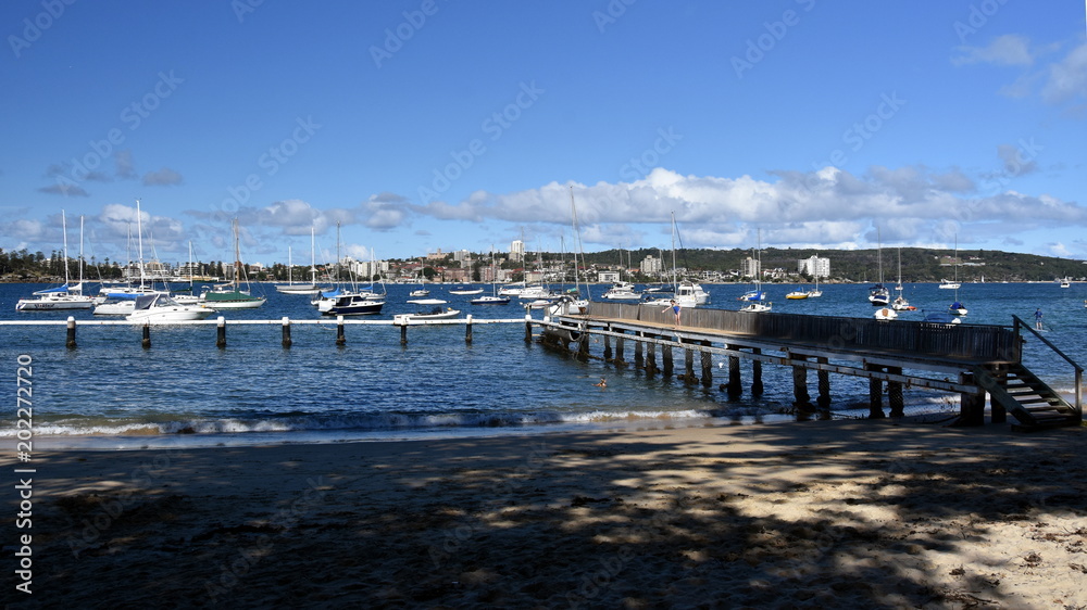 Balgowlah, Australia - Feb 4, 2018. Kids playing at the jetty. Yachts in North Harbour at Fourty Baskets Beach. Manly in the background.