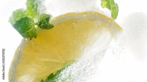 Clooseup slow motion footage from high point of throwing ingredients of lemonade or mojito cocktail in glass photo