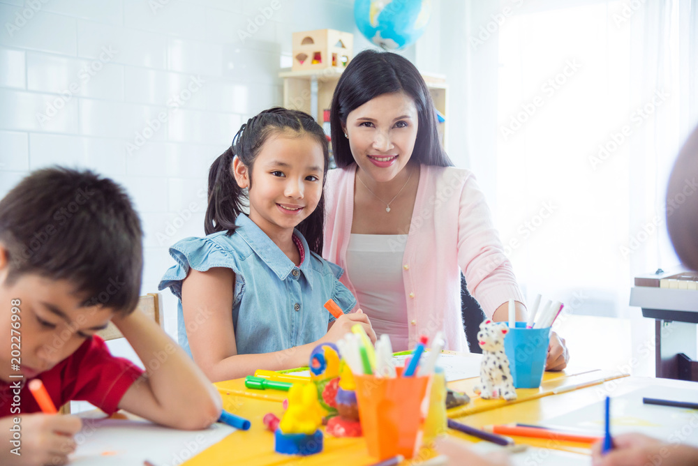 Pretty asian girl and teacher smiling in art classroom