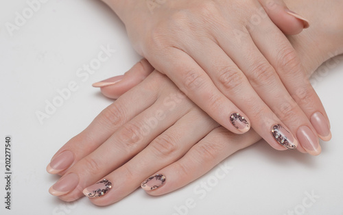 Cute manicure on female hands. Woman hands with black and white design manicure on vintage wooden background. Nails and skin treatment. Matte manicure on female hands.