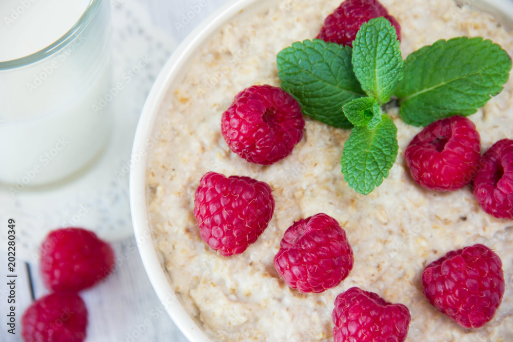 fresh delicious oatmeal with raspberries, next to a mug with milk, a healthy diet, a nutritious breakfast fresh delicious oatmeal with raspberries, next to a mug with milk, a healthy diet, a nutritious breakfast
