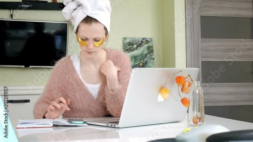 attractive business woman applying cosmetic facial spots at home, working behind laptop photo