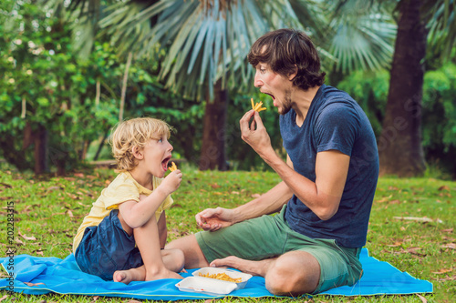 Cute healthy preschool kid boy eats french fries potatoes with ketchup with his father. child eating unhealthy food. photo