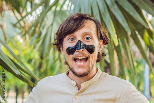 Happy man with black mask on the face. Photo of man receiving spa treatments. Beauty Skin care concept photo