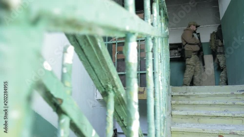 Soldiers in camouflage with combat weapons sneak along the corridors of the old building, the military concept photo