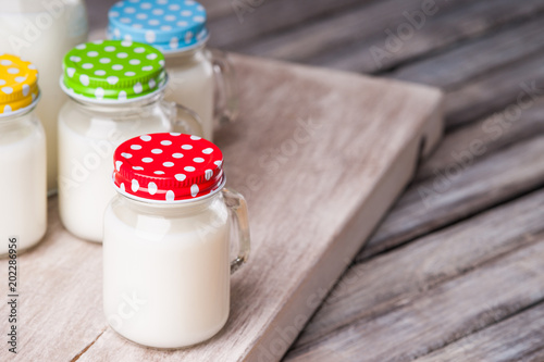 Milk jars with colorful caps on a cutting board 